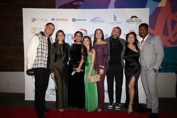 A group of guests in cocktail attire at the step and repeat