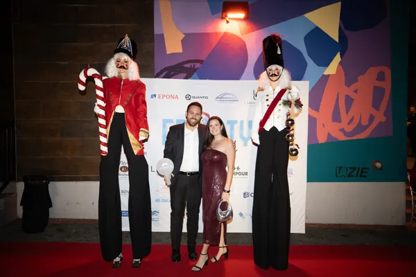 A couple with the nutcracker stilt walkers at the step and repeat